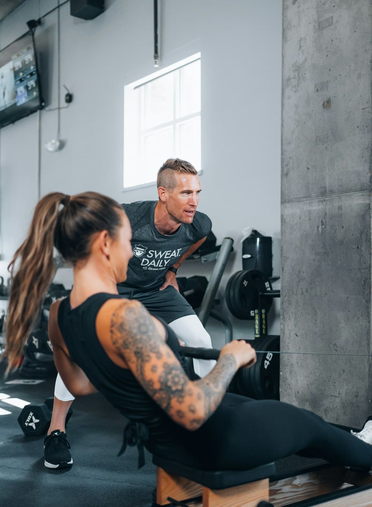 A trainer watches his client's form on a seated row