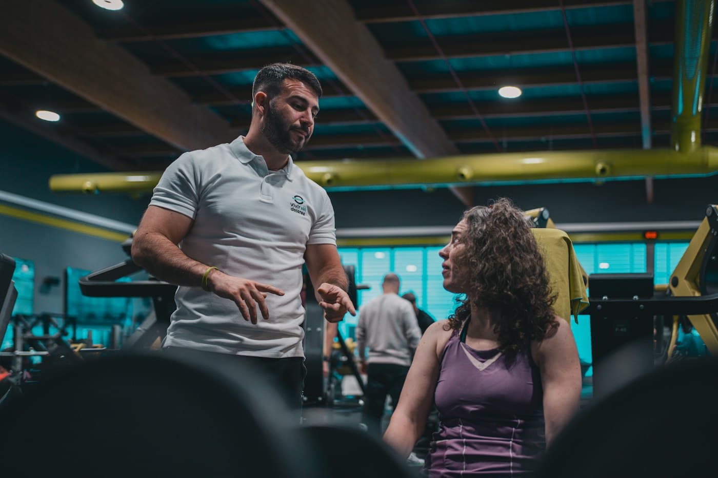 A trainer in the gym explains the next exercise to his client between sets