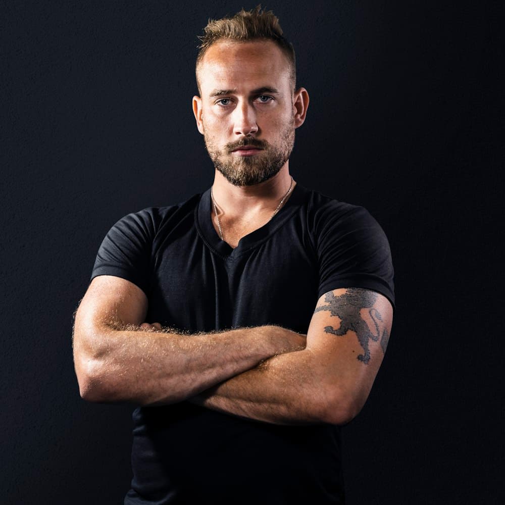 Portrait of a bearded male coach in a black T-shirt, arms crossed